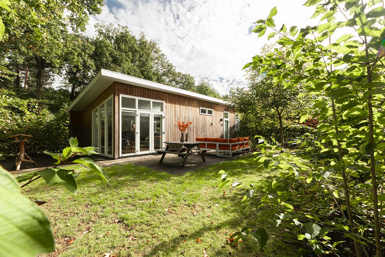 Houten vakantiehuis met terras en picknicktafel in een groene tuin op de Veluwe